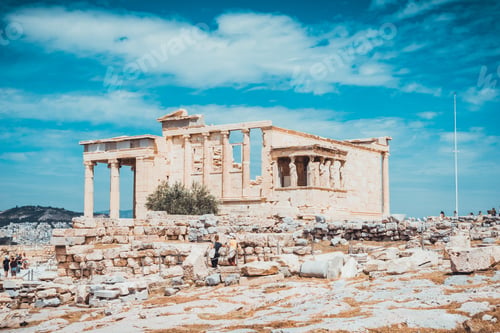 Preview: Old Building In The Greek Acropolis With Other Ruins And Flagpole Nearby Under Blue Sky