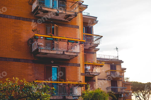 Preview: Balconies On The Corner Of A Colorful Orange Apartment Block Against A Grey Sky In A Close Up View