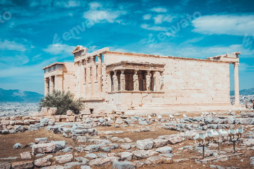 Preview: Ancient Greek Temple Ruins And Foundational Stones In Field Under Blue Sky With Scattered Clouds
