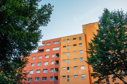 Preview: Red And Orange Apartment Building Inbetween Of Green Trees