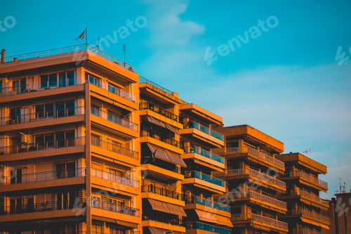 Preview: Apartment Block With Balconies Lit By A Golden Glow At Sunset Against A Blue Sky At Dusk