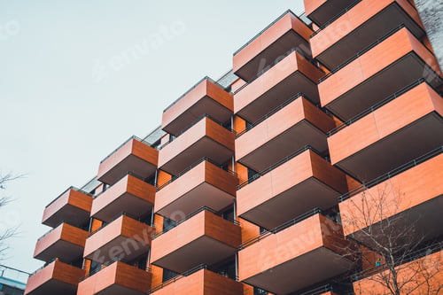 Preview: Front Low Angle View Of Housing Complex With Orange Colored Balconies Under A Grey Sky
