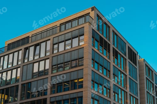 Preview: Condominum Exterior With Slanted Windows And Wide Upper Level Patio. Clear Sky Reflecting In Glass.