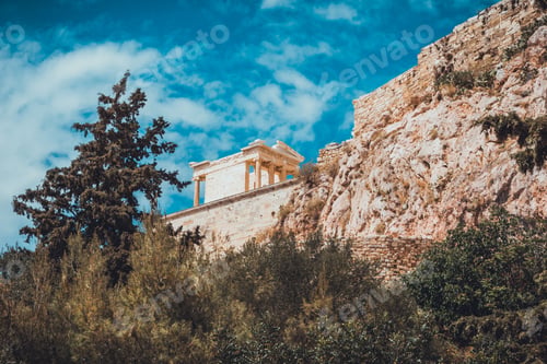 Preview: Old Greek Temple On Cliff With Rocks And Various Trees And Shrubs Under Blue Sky With Scattered