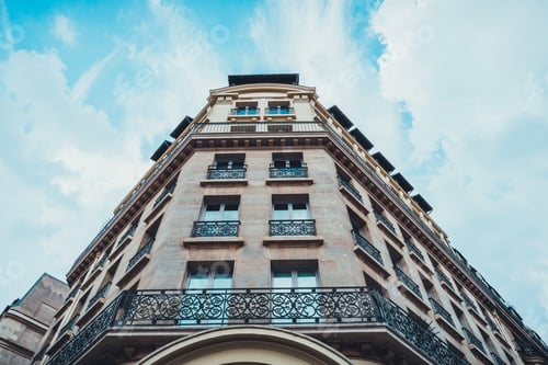 Preview: Low Angle Exterior View On Beveled Corner Section Of Stone Block Apartments Under Partly Cloudy Sky