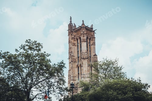 Preview: Tall Historic Cathedral Tower For Church Surrounded By Trees Under Partly Cloudy Sky