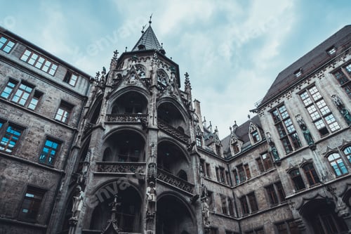 Preview: Old Gothic Style Tower With Arched Balconies Above Building Under Blue Sky With Scattered Clouds