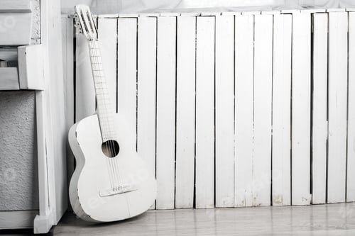Preview: Old Acoustic Guitar Leaning Against The White Wooden Wall