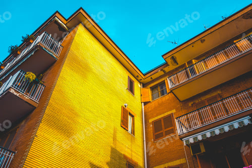 Preview: Colorful Yellow Apartment Block Detail At Sunset Looking Up At The Golden Glow On The Wall Under A