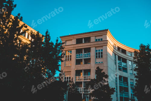 Preview: Curved Historical Urban Buildings Surrounded By Green Trees At Sunset Under A Clear Blue Sky
