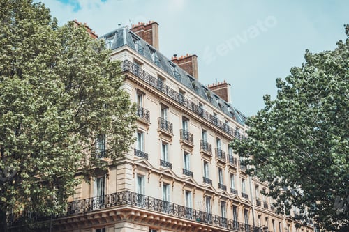 Preview: Two Large Green Trees At Sides Of Six Story High Light Brown Colored Apartment Building