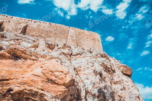 Preview: Walls Of Ancient Acropolis On High Cliff In Greece With Deep Blue Sky Filled With Scattered Clouds
