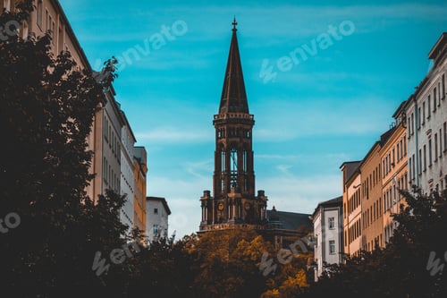 Preview: Tall Spire On A Cathedral Or Church Bewteen Multi-Storey Office Or Apartment Buildings In Evening