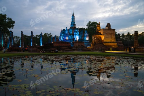 Vista previa: Ruins Of The Buddhist Temple Of Wat Mahathat In Blue Illuminated By A Cloudy Evening. Sukhothai