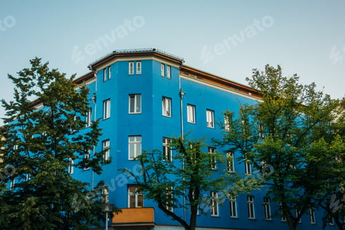 Preview: Blue Corner House On Darken Sky Inbetween Of Green Trees