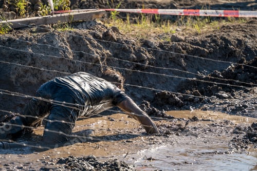Preview: Athlete Crawling Under Barbed Wire In Dirty Mud, Obstacle Course Race
