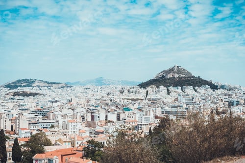 Preview: View Of City And Pair Of Famous Hills In Greece Under Daytime Sky With Scattered Clouds