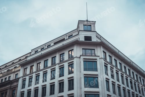 Preview: Low Angle View On Building With Three Pane Mullion Type Windows On Beveled Corner Under Gray Sky