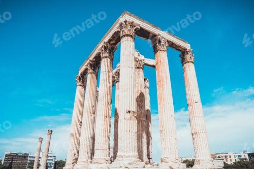 Preview: Columns Made From Carved Stone For Ancient Building Under Blue Sky With Modern Buildings In The