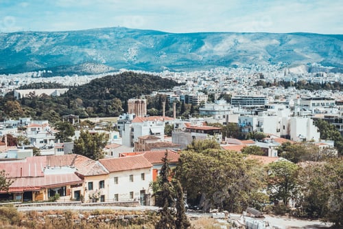 Preview: Various Apartments And Houses Leading Down To City From Hill In Greece With Mountain In Background
