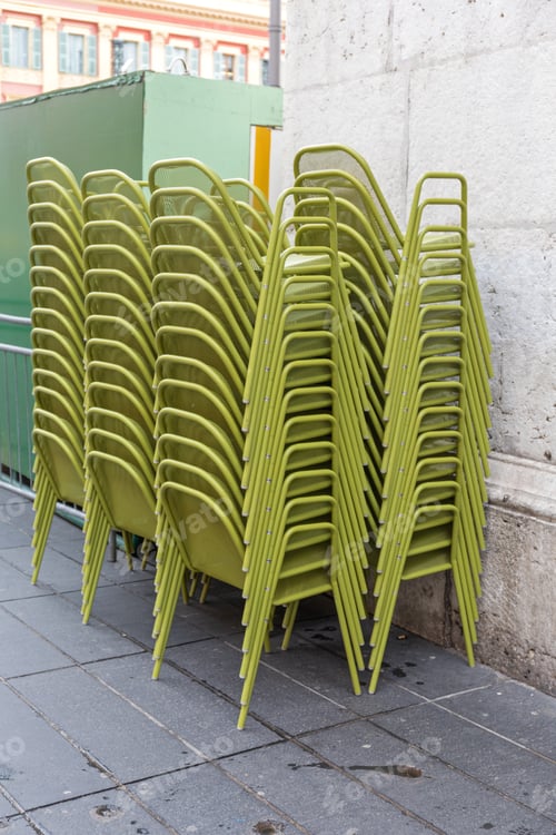 Preview: Stacked Green Metal Chairs In Front Of Restaurant