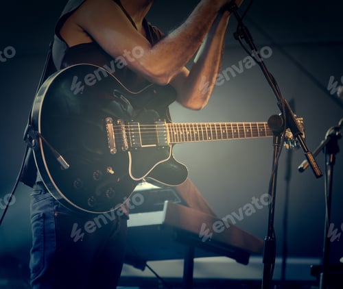 Preview: Musician Playing Guitar in Concert with Dark Lighting