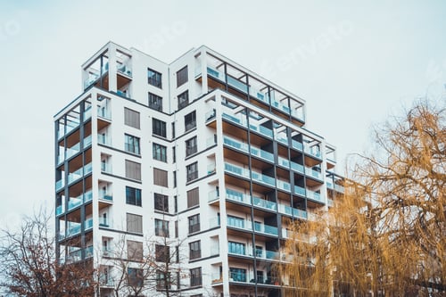 Preview: Low Angle View On Tall Luxury Of Apartment Building With Open Roof Balconies And Large Tree In