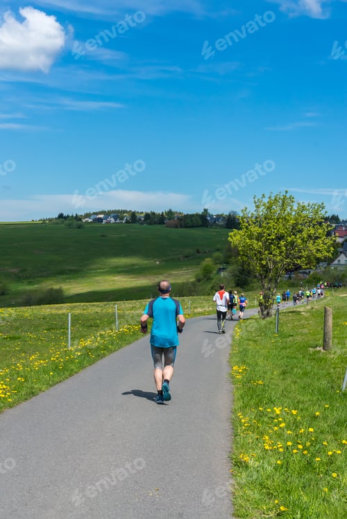 Preview: People Running A Marathon On A Road In Beautiful Landscape