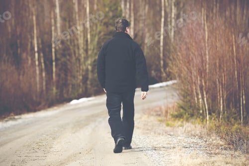 Preview: An Older Man Is Walking On The Road. He Is Walking Away. The Man Is Wearing Dark Jeans And A Black