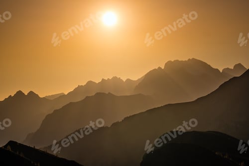 Preview: Sun Glow In Evening Hazy Sky And Mountain Silhouettes View. Peaceful View From Giau Pass. Climate
