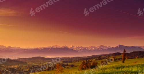 Preview: Small Swiss Town Surrounded By Meadows On The Background Of Snow-Capped Alps