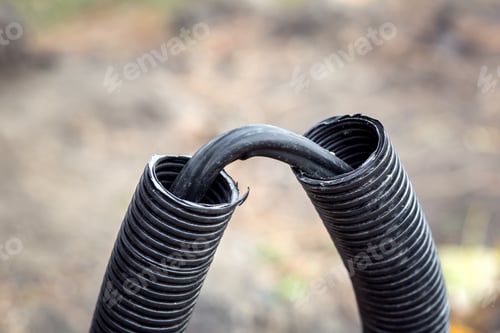 Preview: Cable With Black Insulation In A Corrugated Black Plastic Cover On The Ground.