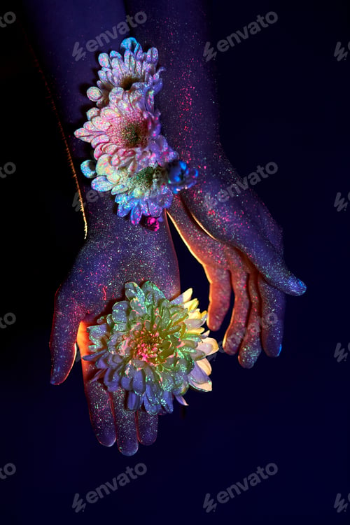Preview: Beauty Hands Of A Woman In Ultraviolet Light With Flowers In The Palms. Cosmetics For Hand Skin Care