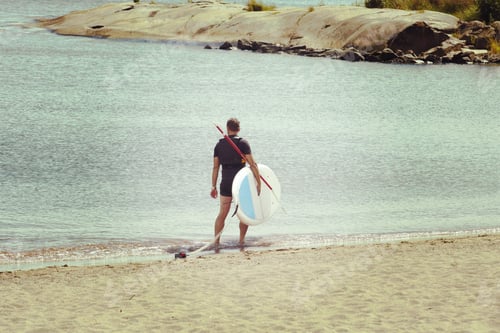 Preview: A Male Surfer Is Carrying The Surf Board On The Beach After A Surfing Session. Image Has A Vintage