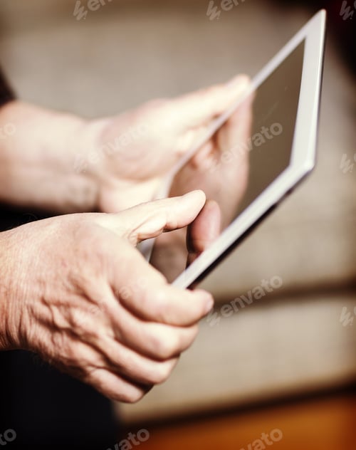 Preview: An Elderly Man Browsing The Internet With A Tablet In A Living Room And Sitting In A Sofa. Image