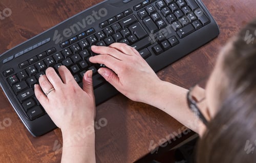 Preview: A Woman Is Writing A Document. The Wireless Keyboard Is On A Wooden Table. The Keyboard Is Black.