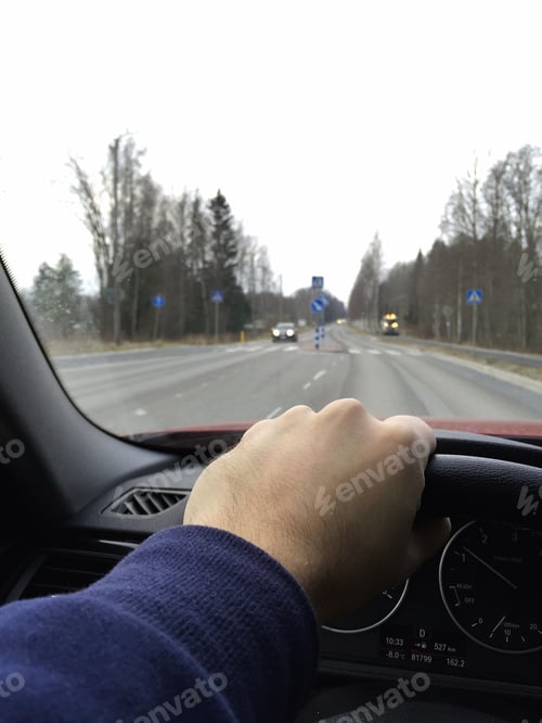 Preview: A Man Is Driving A Modern Car With One Hand Holding The Steering Wheel. Focus Point On The Hand.