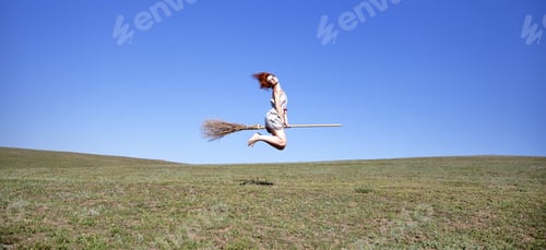 Preview: Young Red-Haired Witch On Broom Flying Over Green Grass Field