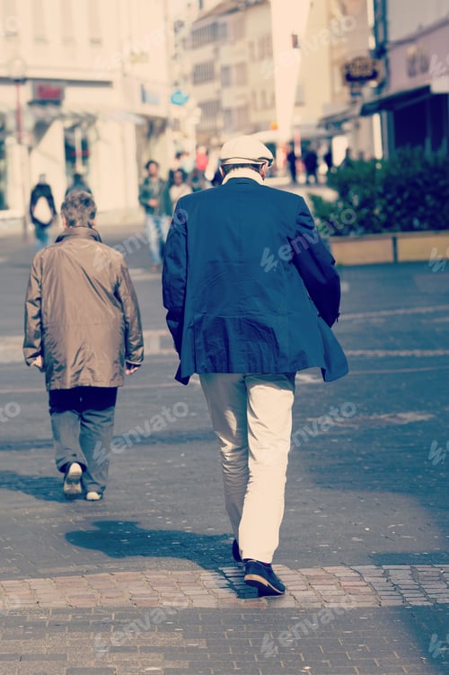 Preview: A Man Is Walking In The Streets. The Man Has A White Cap And White Trousers With Blue Jacket. Image