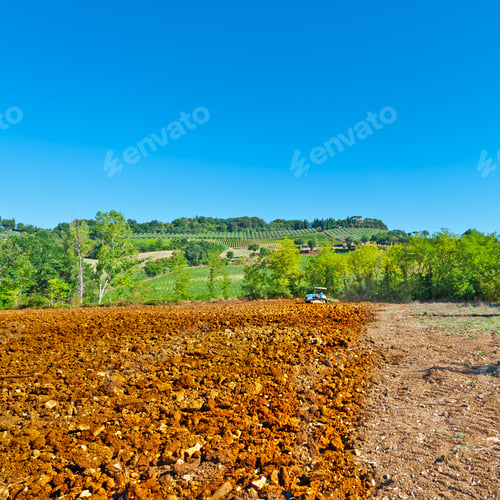 Preview: Tractor Plowing Field On A Background Of Vineyards In Tuscany, Italy