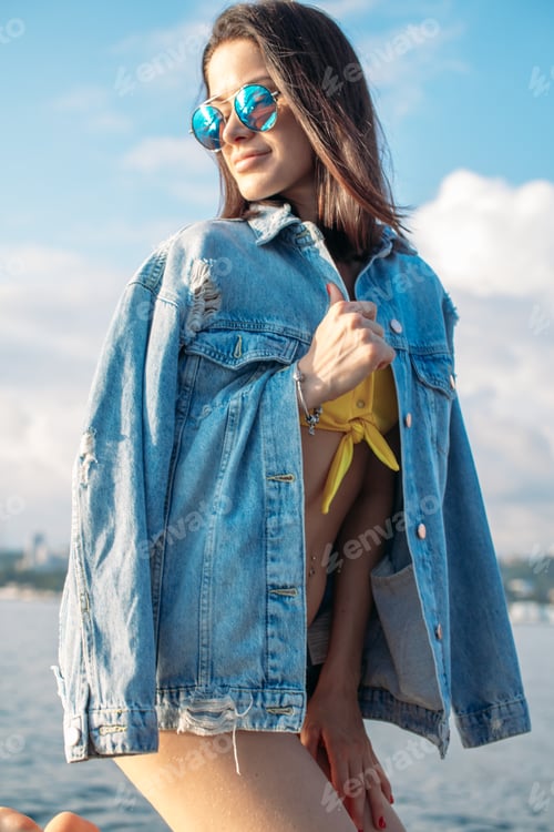 Preview: Beautiful Young Girl In Bikini A Little Bit Cold On Fresh Sea Breeze, Wearing Denim Jacket Over