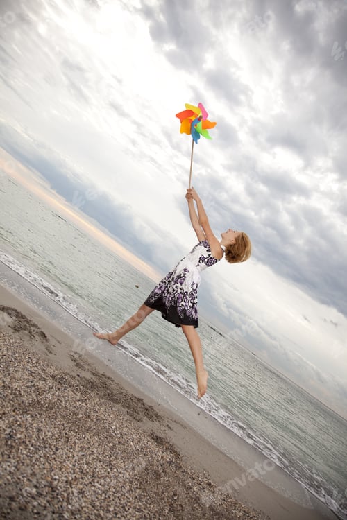 Preview: Blonde Girl Jumping With Wind Turbine At Beach.