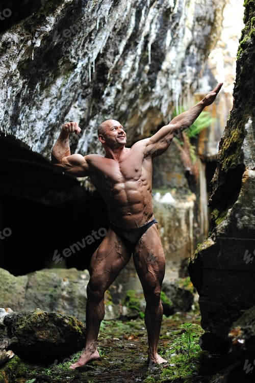 Preview: Young Bodybuilder Posing In A Cave - Front View In Full Length Portrait