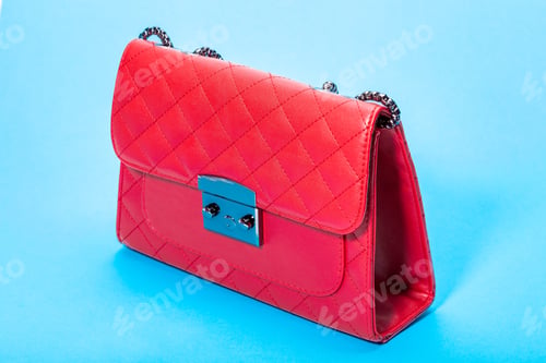 Preview: Woman`S Handbag In Red Leather With Square Pattern, Side View Object On A Blue Background.