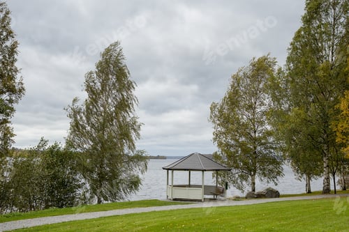 Preview: Day At The Park Next To A Big Lake. A Small Building Is In The Front. Image Taken On A Cloudy And