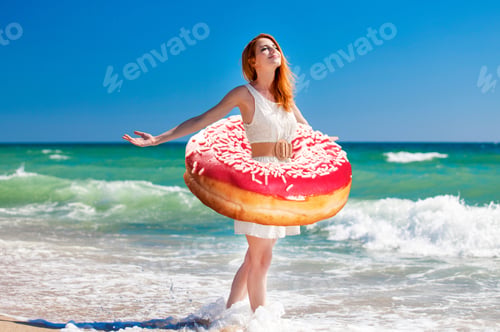 Preview: Young Redhead Girl With Donut At The Waist Walking On The Coast Line