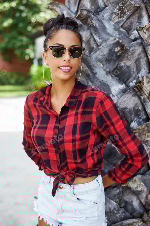 Preview: Young Woman in Plaid Shirt Leaning Against Tree