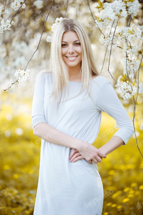 Preview: Beautiful Young Blonde Woman In The Park With White Flowers On A Warm Summer Day