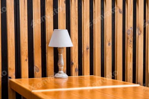 Preview: A Retro Style Wooden Table Lamp Stands On An Empty Table By The Decorative Wall Of Brown Planks And