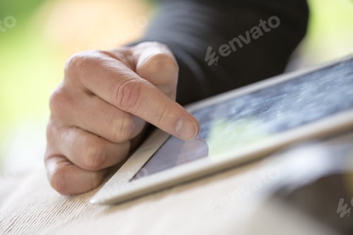 Preview: An Older Man Is Browsing The Internet With A White Tablet Outdoor.